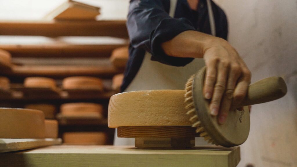 Una contadina mentre si prende cura dei formaggi in cantina.

