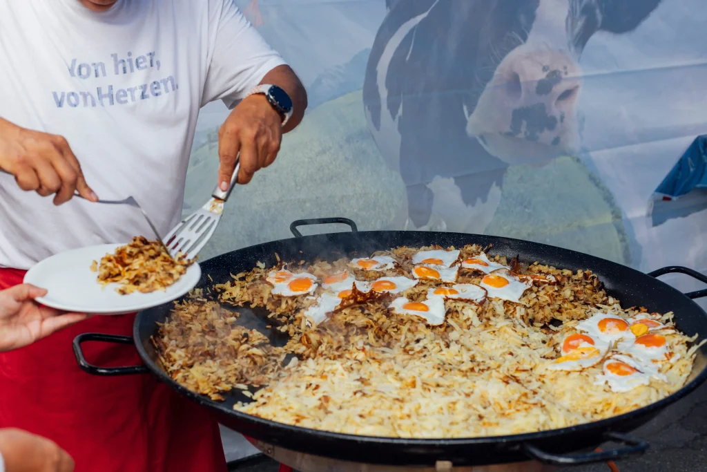 Una persona serve rösti e uova al tegamino direttamente dalla padella.